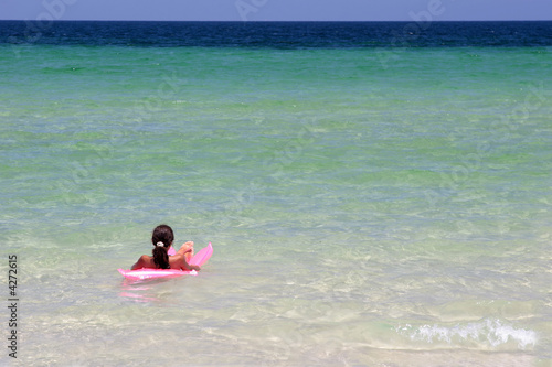 Young girl on pink air-bed in the sea © Tomasz Szymanski