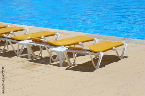 pool restbeds around a pool with blue water background