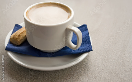 left aligned flat white coffee with biscotti on blue napkin