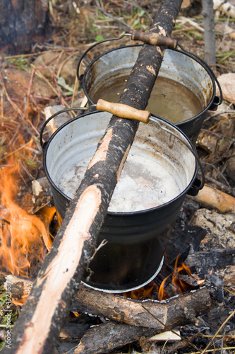 Boiling water in pails above the fire in camping