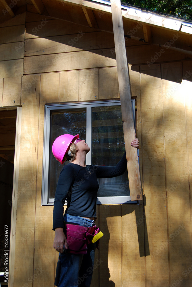 Female construction worker lifts wood Female construction worker lifts wood