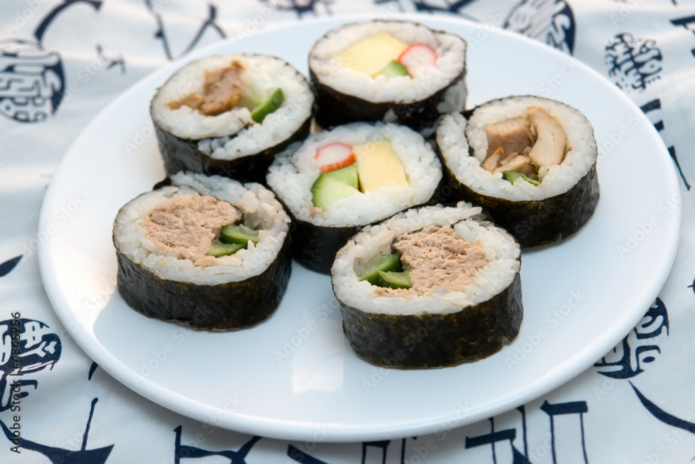sushi rolls on round plate on white kimono background sushi rolls on round plate on white kimono background