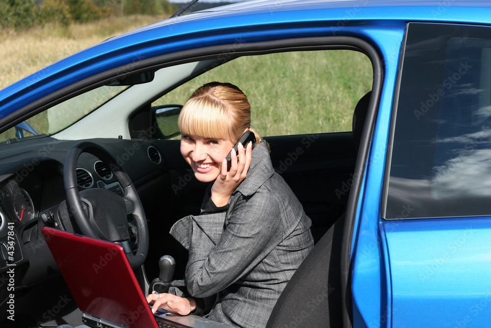 young woman with notebook in a car with phone young woman with notebook in a car with phone