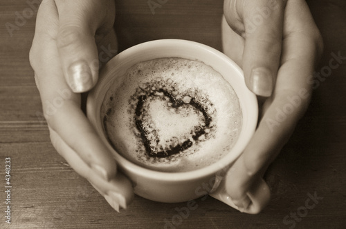 Hands Holding Coffee with Cocoa Heart in the Cup photo