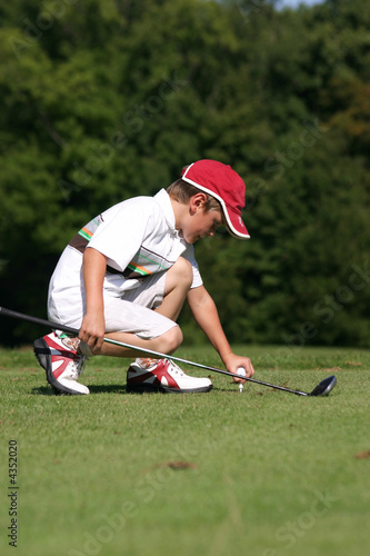 petit golfeur plante un tee