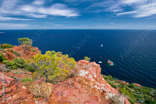 Rochers rouge avec peu de vegetation à la bord de la mer.