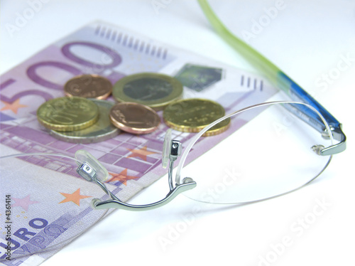 Liegende Brille auf 500-Euroschein mit Münzen