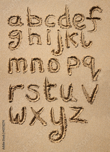 The alphabet written in sand on a beach.