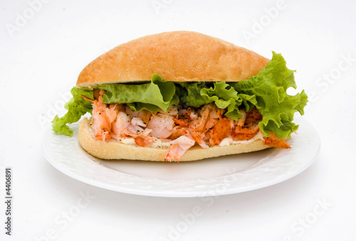 A delicious lobster sandwich with lettuce and a bun.