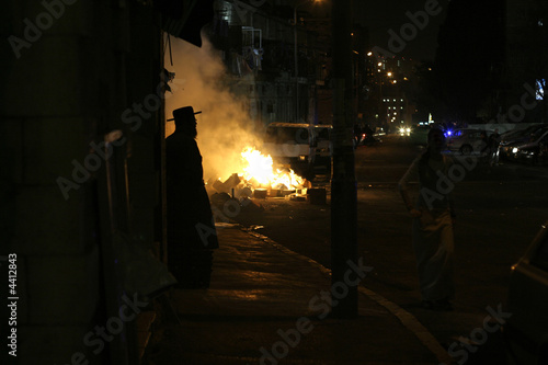 фотографія silhouette of hasidic jew standing in front of  riot fires