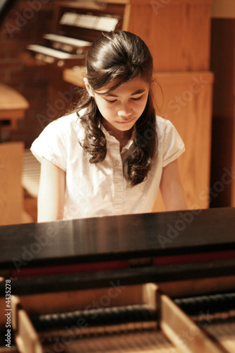 Young teen girl playing the grand piano