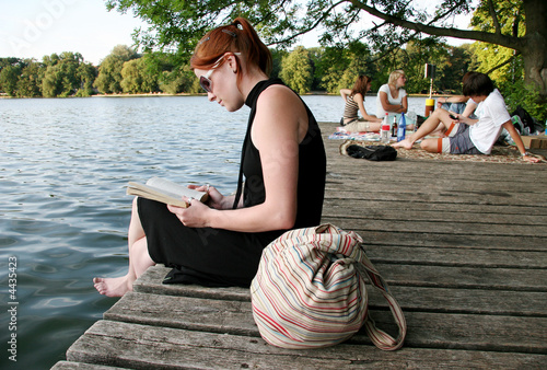 Young woman reading at lake