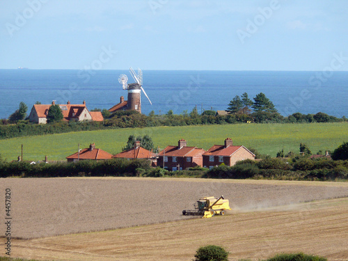 Combine harvester  with windmill and Norfolk Coast i