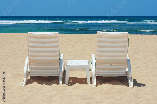Two beach chairs on beach sand