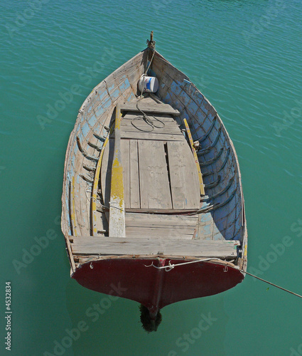 Old wooden open rowing dinghy in a green sea