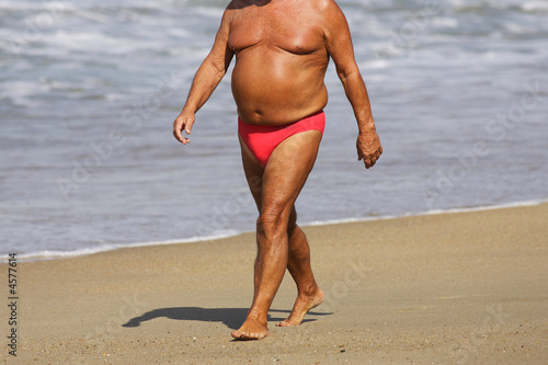 homme avec embonpoint qui marche sur la plage