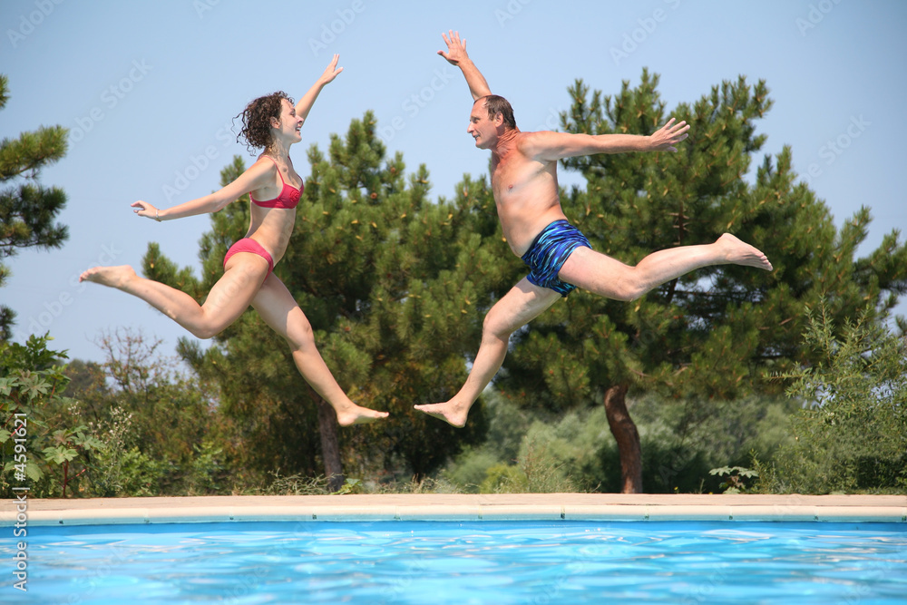 man and woman jumping under the pool