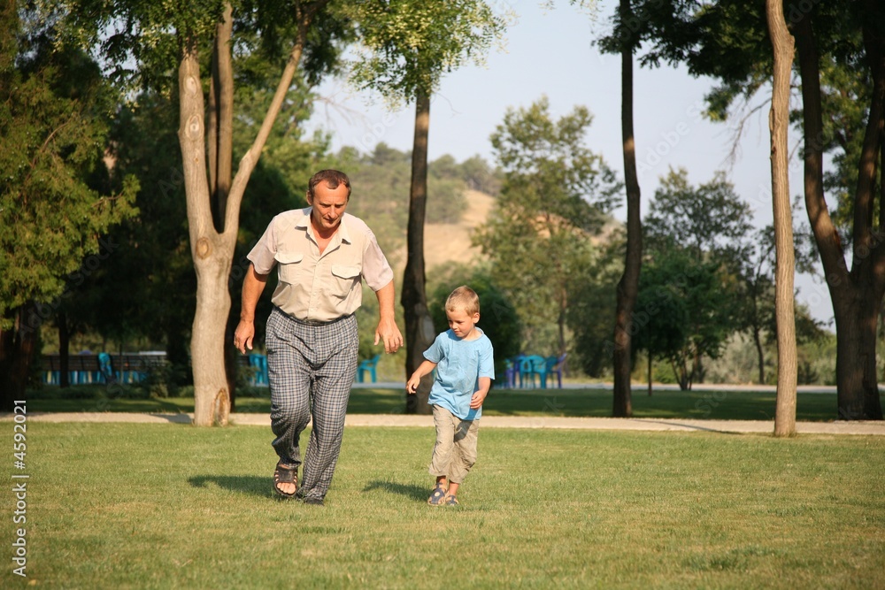 Fototapeta premium Grandfather with grandson runing on the park