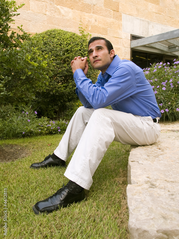 hispanic businessman sitting on rock hispanic businessman sitting on rock