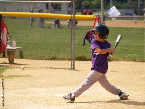 young baseball player after swinging watching ball