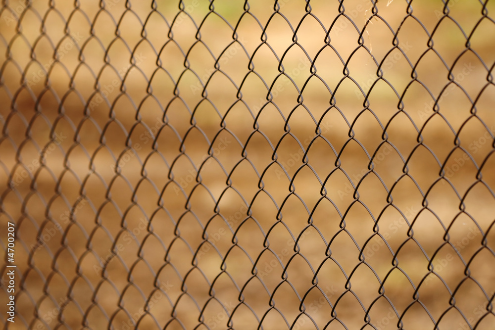 Chainlink fence against brown background - depth of field Chainlink fence against brown background - depth of field