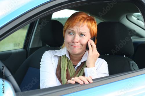 Red-haired woman with mobile-phone in a car. 