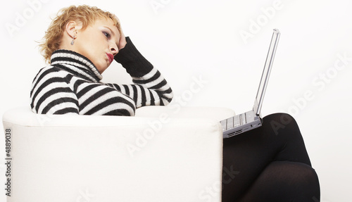 Nice blondgirl sitting on the chair with laptop  photo