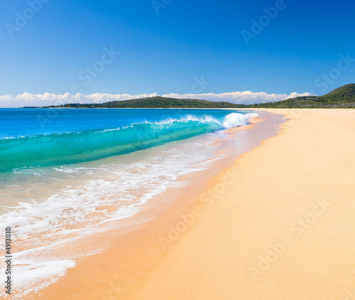 A Perfect wave rolls onto the beach