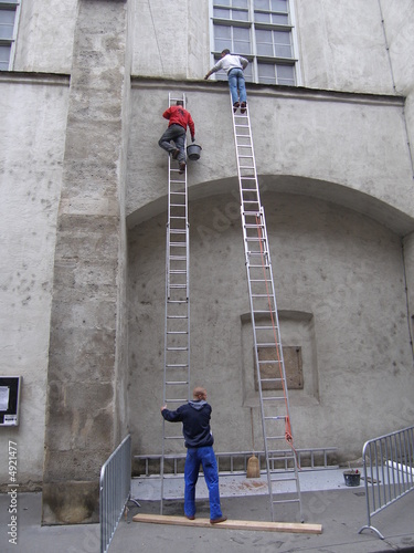 drei männer mit leitern beim reinigen einer fassade