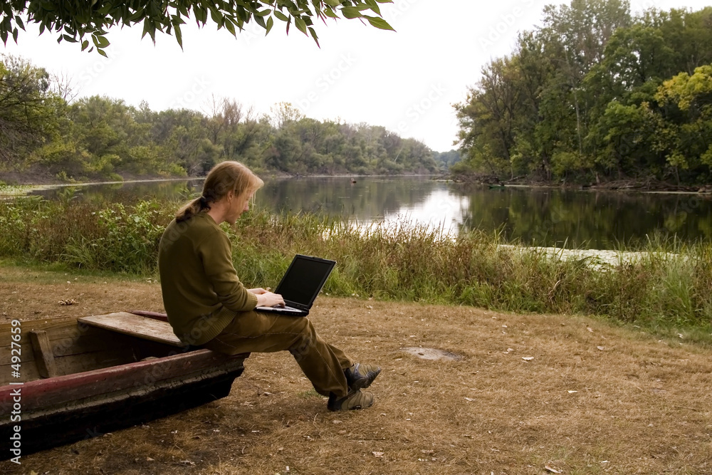 A man is working with her nootebook in outdoors A man is working with her nootebook in outdoors