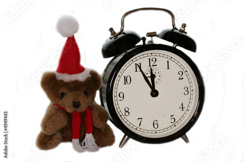 teddy bear in christmas red cap and old alarm clock
