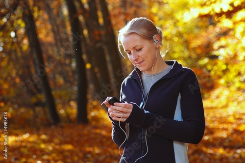 Young, sporty woman listening music in the park
