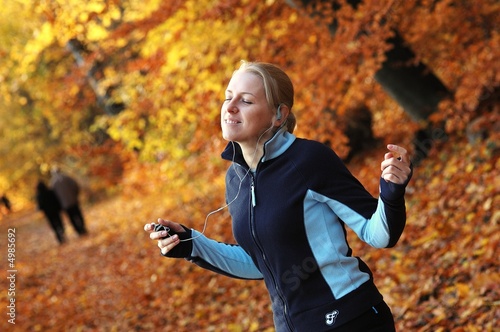 Young, sporty woman listening music in the park