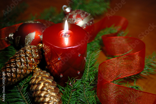 red candle and glass christmas ornaments on table