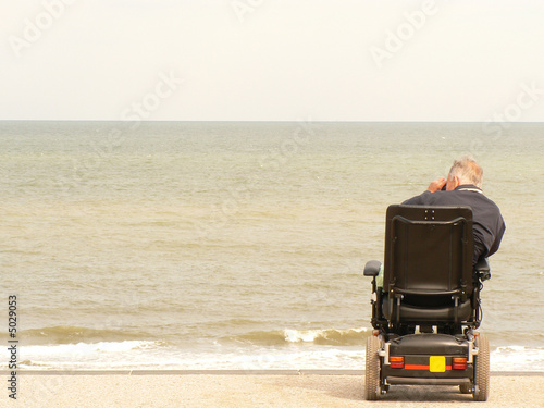 man in wheel chair with binoculars observing ocean