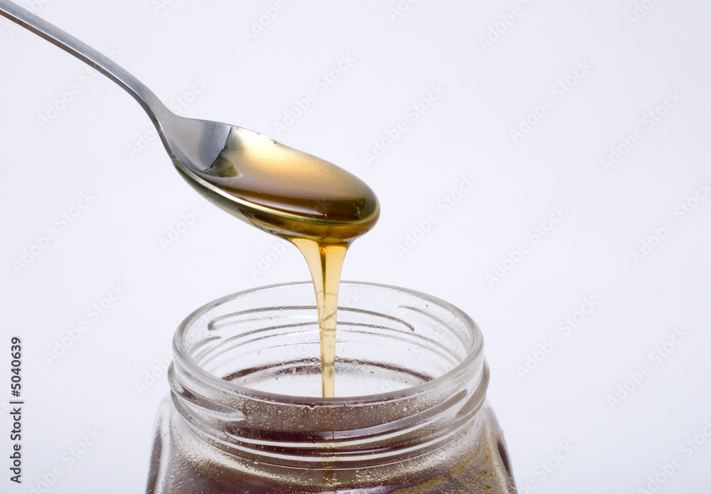 spoon full of honey above glass pot spoon full of honey above glass pot