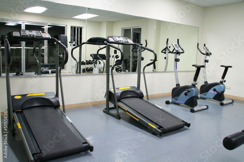exercise gym with large mirrors, treadmills and stationary bikes