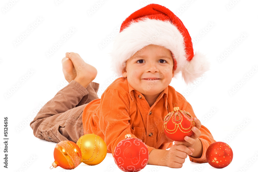Boy in santa hat laying among christmas baubles - isolated Boy in santa hat laying among christmas baubles - isolated