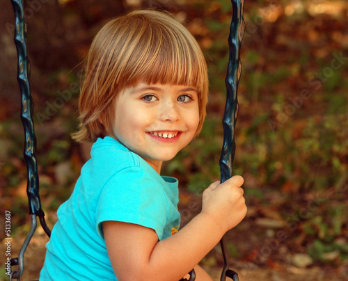 Little girl playing on a swing