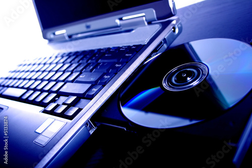 laptop with a disk dvd. blue tone photo