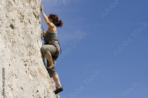 Jeune femme escaladant une falaise
