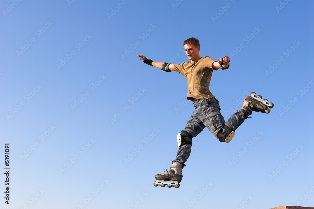 Roller boy jumping from parapet on the blue sky Roller boy jumping from parapet on the blue sky