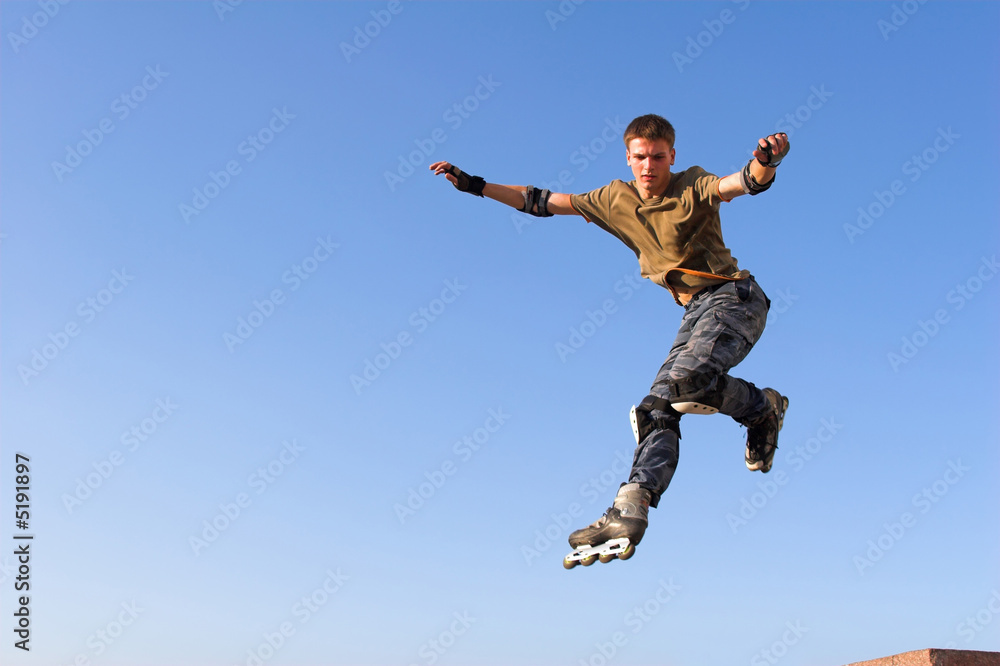 Roller boy jumping from parapet on the blue sky Roller boy jumping from parapet on the blue sky