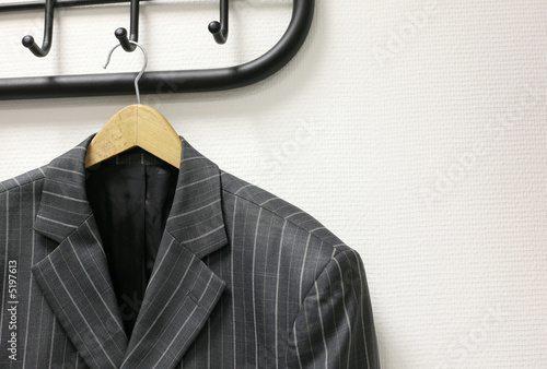 Man's jacket hanging on a coat hanger at a wall