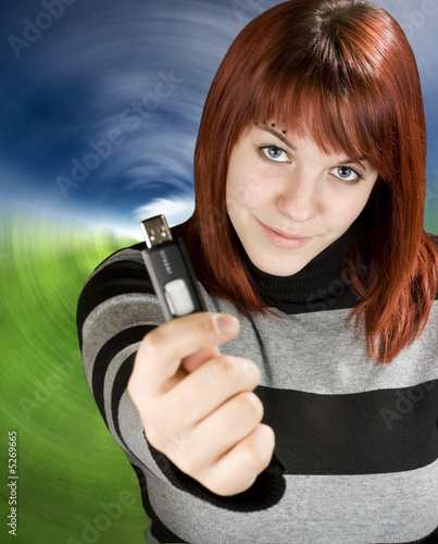 Redhead girl holding a flash drive at camera