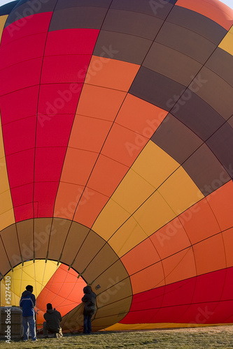 Inflating a colorful hot air balloon, crew silhouettes
