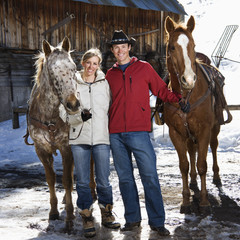 Couple holding horses.