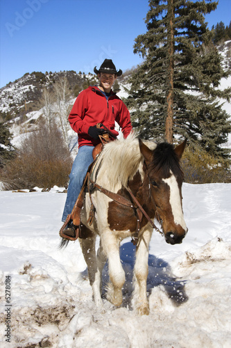 Man horseback riding in snow.