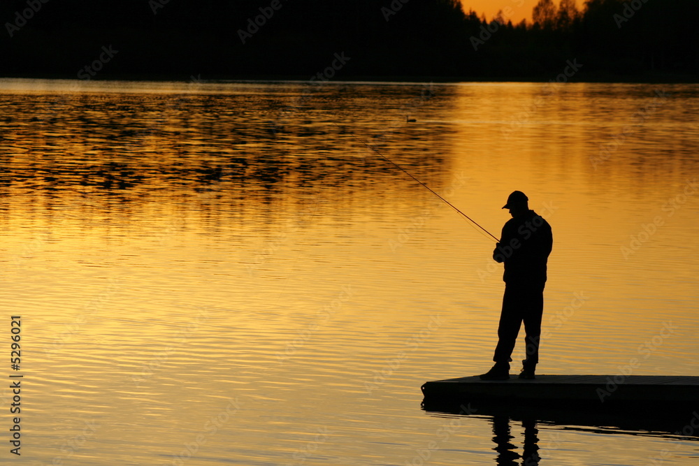 A silhouette of a fisherman as the sunset on lower. A silhouette of a fisherman as the sunset on lower.