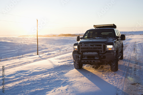 Truck on ice covered road and snowy rural landscape. © iofoto
